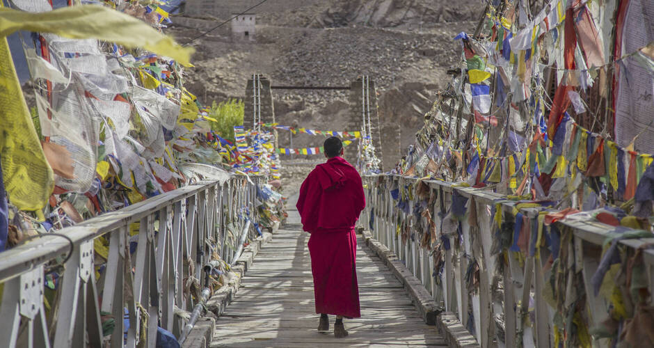Mönch auf einer Brücke zwischen Gebetsfahnen 
