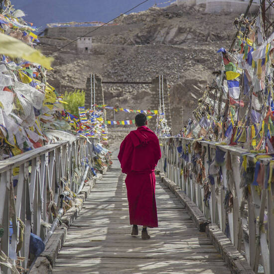 Mönch auf einer Brücke zwischen Gebetsfahnen 